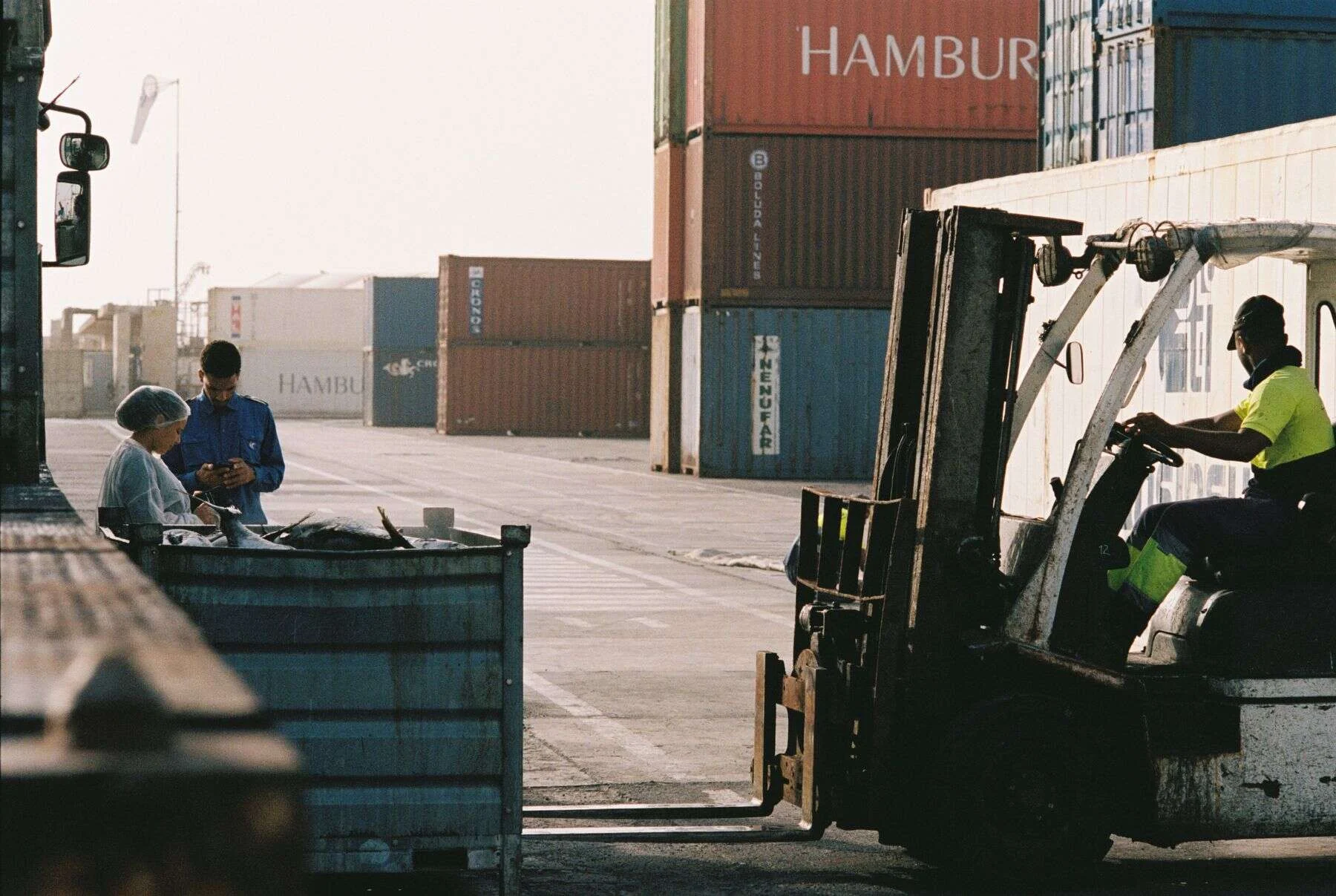 Forklift and workers handling containers at a port