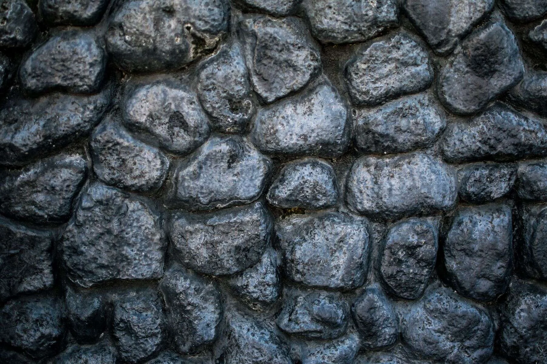 Grey basalt stone wall with rounded blocks
