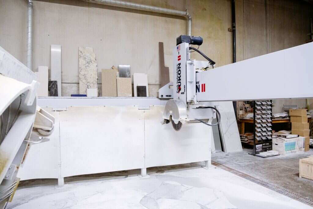 Industrial bridge saw cutting a white stone slab in a factory