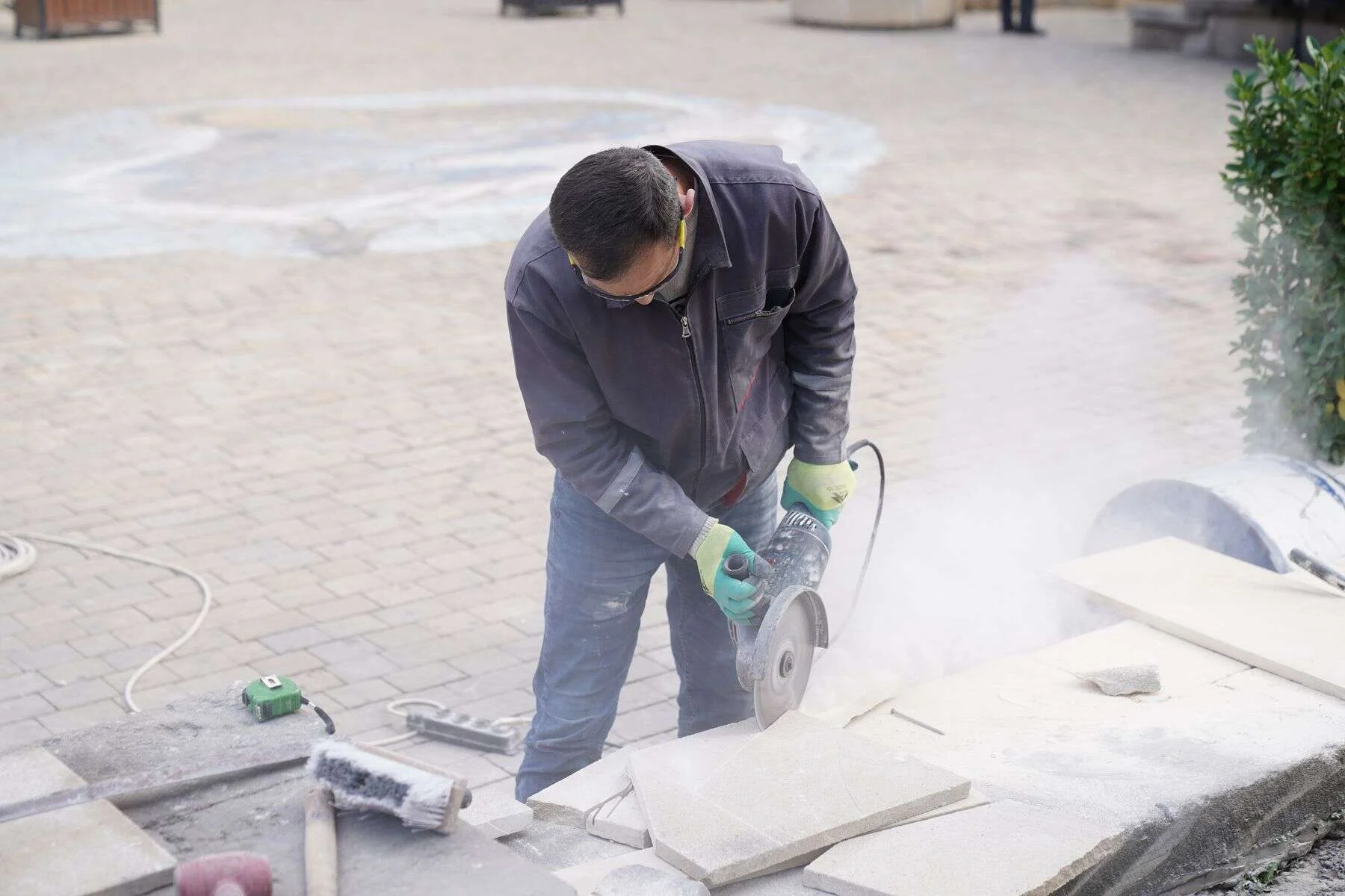 Worker cutting a stone tile with an angle grinder