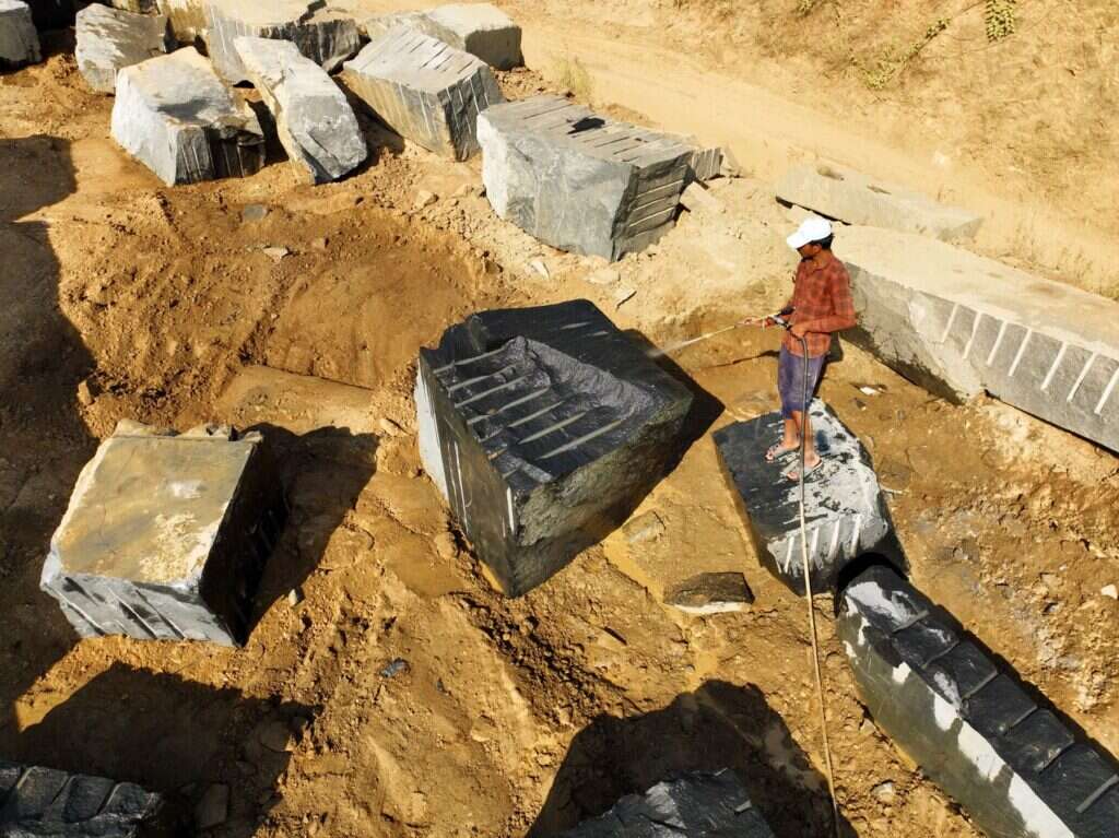 Quarry worker standing next to freshly cut granite blocks