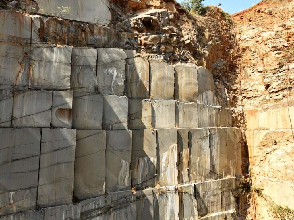 Sunlit granite quarry wall cut into neat rectangular blocks