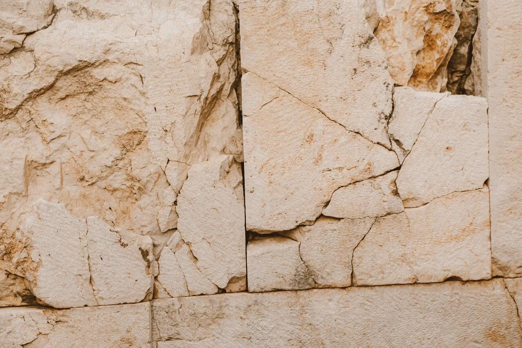 Cracked limestone rock face in warm beige